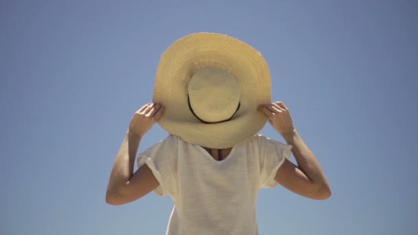 Mujer con sombrero de pie contra el cielo azul — Vídeo de stock