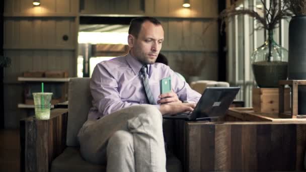 Homme d'affaires avec smartphone et ordinateur portable assis dans un café — Video