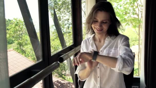 Kvinna med smartwatch stående genom fönstret — Stockvideo