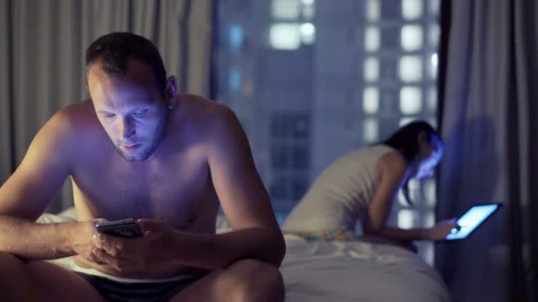 Casal usando smartphone e tablet no quarto — Vídeo de Stock