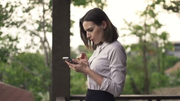 Jonge zakenvrouw met smartphone op terras — Stockvideo