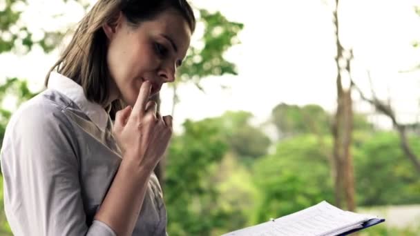 Jonge zakenvrouw lezen van de krant op terras — Stockvideo