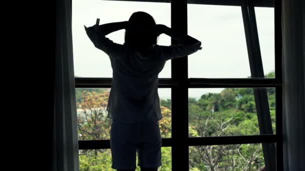 Mujer estirando los brazos de pie por la ventana — Vídeos de Stock