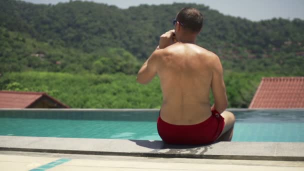 Mann entspannt sich und trinkt Bier am Pool — Stockvideo