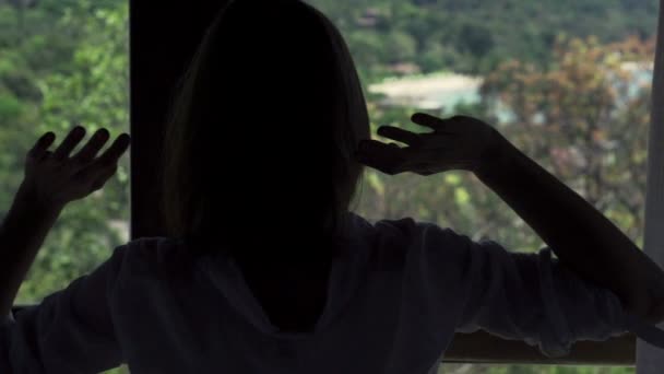Женщина вытягивает руки к окну — стоковое видео