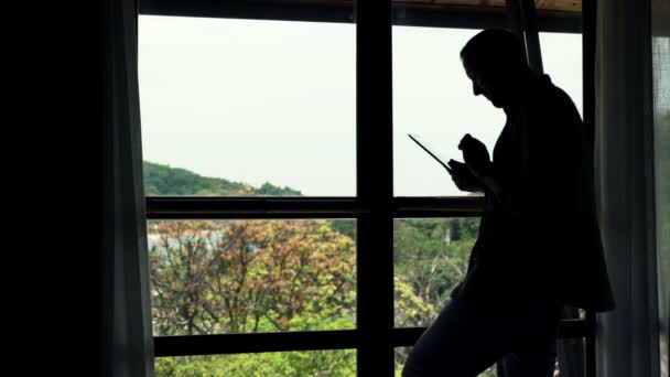 Człowiek przy użyciu komputera typu tablet przez okno — Wideo stockowe