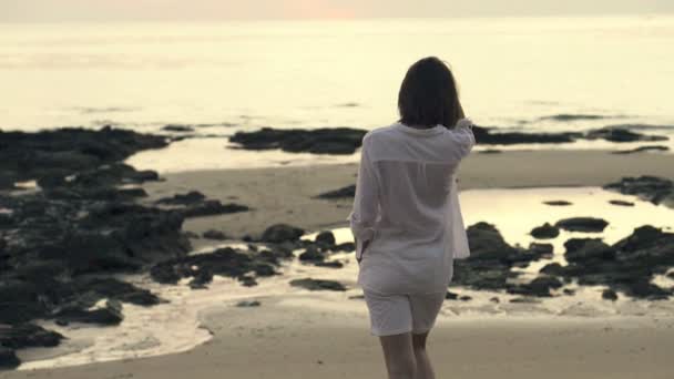 Жінка ходить на пляжі ввечері — стокове відео
