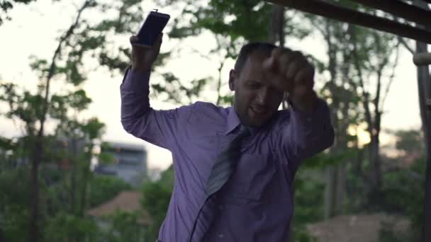 Бизнесмен слушает музыку, танцует на террасе — стоковое видео