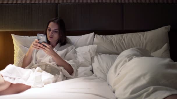 Mujer usando teléfono inteligente y hombre durmiendo — Vídeo de stock