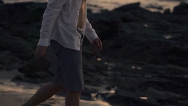 Man promenerar på stranden under solnedgången — Stockvideo