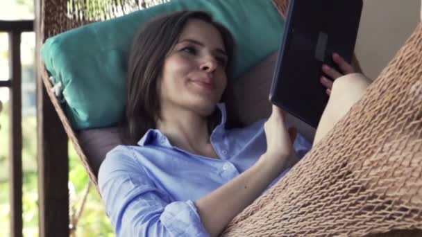 Kobieta z komputera typu tablet leżącego na hamaku — Wideo stockowe