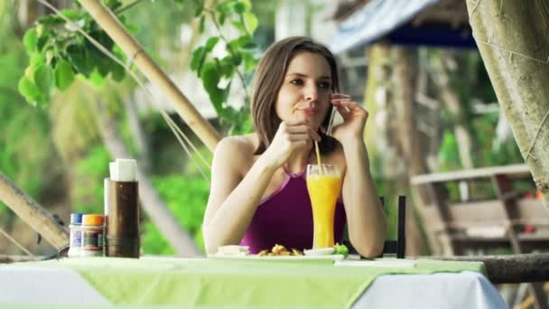 Femeie vorbind pe telefon mobil și bea suc în cafenea — Videoclip de stoc
