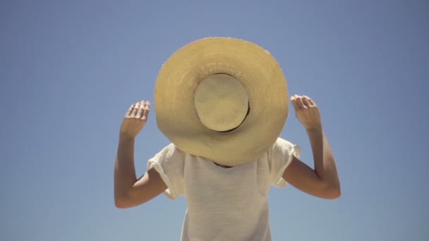 Mujer con sombrero de pie contra el cielo azul — Vídeos de Stock