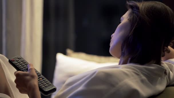 Mujer viendo televisión sentada en un sofá — Vídeos de Stock