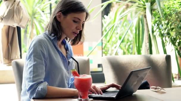 Woman using laptop and drinking cocktail — Stock Video