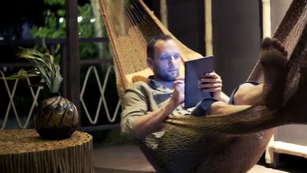 Man with tablet computer lying on hammock — Stock Video