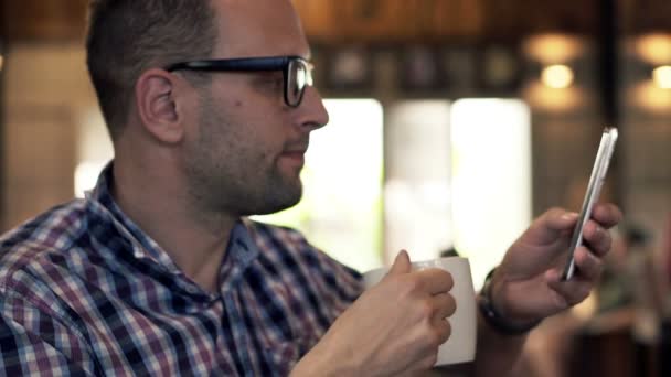 Man with smartphone drinking coffee in cafe — Stock Video