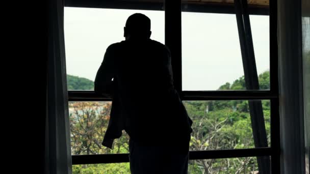 Ο άνθρωπος, θαυμάζοντας τη θέα ενώ στέκεται από το παράθυρο — Αρχείο Βίντεο