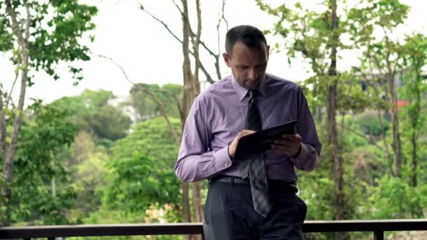 Бізнесмен використовує планшетний комп'ютер на терасі — стокове відео