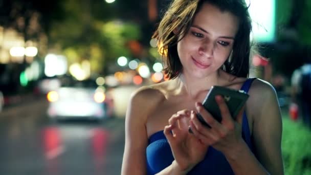 Frau mit Smartphone steht nachts in der Stadt — Stockvideo