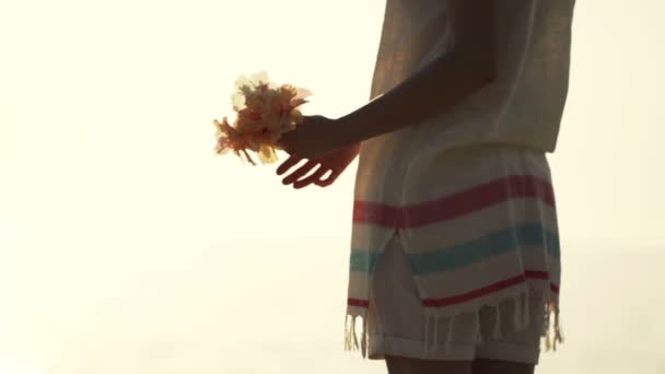 Kvinnan som kastar blommor på stranden — Stockvideo