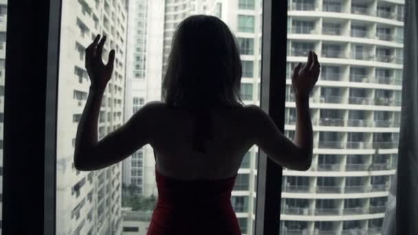 Mujer estirando los brazos y admirar la vista desde la ventana — Vídeo de stock