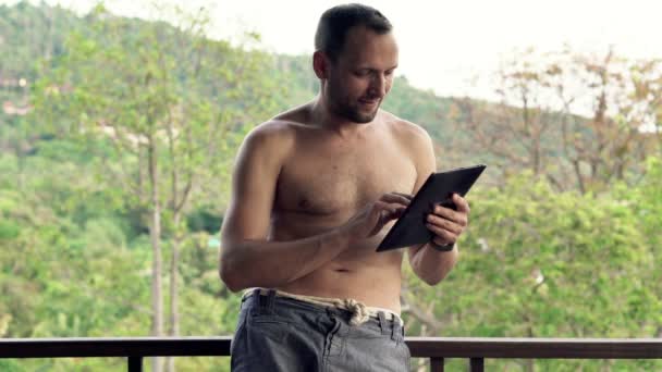 Man using tablet computer standing on terrace — Stock Video
