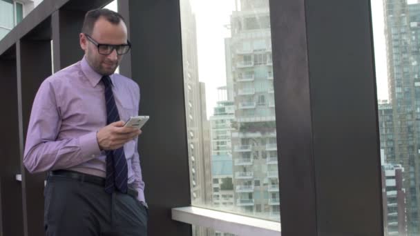 Uomo d'affari utilizzando smartphone in piedi sulla terrazza — Video Stock