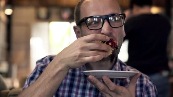 Mann isst leckeres, süßes Brötchen im Café — Stockvideo