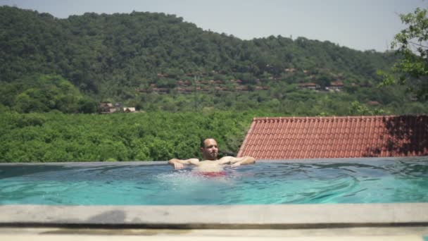 Hombre joven relajándose en la piscina — Vídeos de Stock