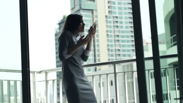Злая деловая женщина разговаривает по мобильному телефону на террасе — стоковое видео