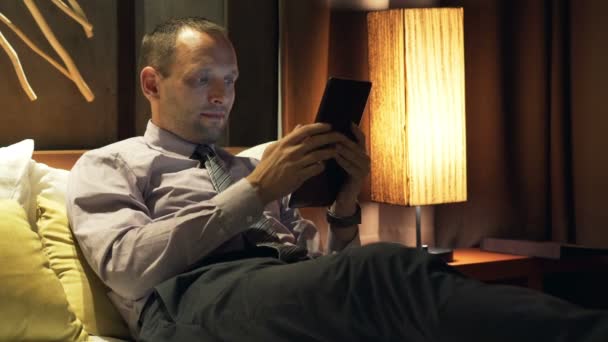 Homme d'affaires avec tablette d'ordinateur couché sur le lit — Video