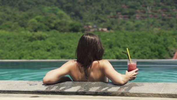 Frau im Schwimmbad entspannt sich mit Cocktail — Stockvideo