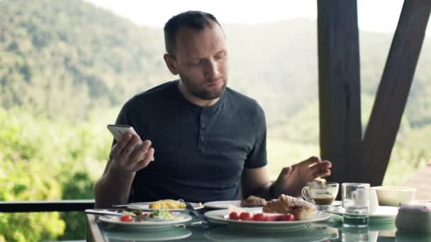 Man använder smartphone under frukost — Stockvideo