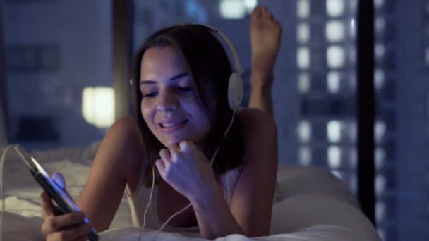 Mujer escuchar música en el teléfono celular en la cama — Vídeo de stock