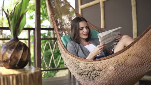 Businesswoman reading newspaper on hammock on terrace — Stock Video
