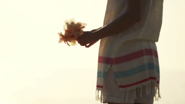 Женщина выбрасывает цветы на пляж — стоковое видео