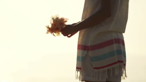 Woman throwing away flowers on the beach — Stock Video