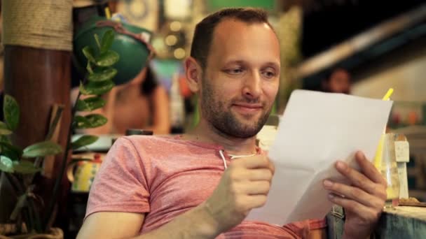 Hombre leyendo carta sentado en la cafetería — Vídeo de stock