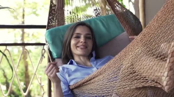 Kvinnan talar med kameran ligger på hammock — Stockvideo
