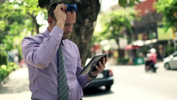 Businessman with tablet computer standing by street — Stock Video