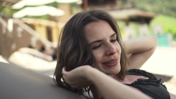 Vrouw speelt met haar op de zonnebank bij zwembad — Stockvideo