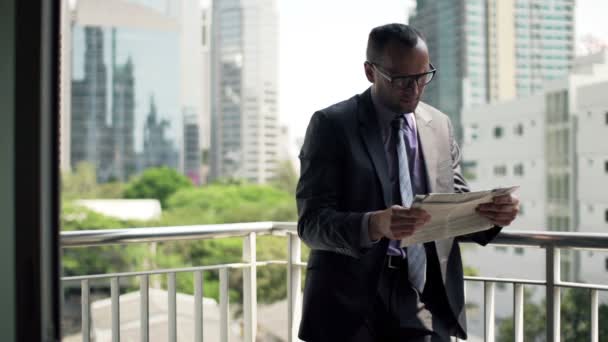 Бизнесмен читает газету на террасе — стоковое видео