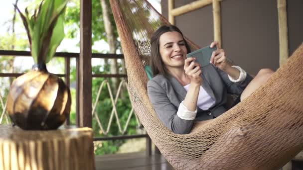 Mujer de negocios jugando juego en el teléfono inteligente en hamaca — Vídeos de Stock