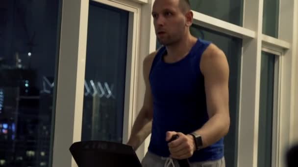 Мужчина тренируется на эллиптической машине в тренажерном зале — стоковое видео