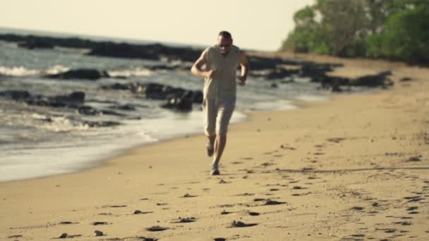 Junger Mann joggt am Strand — Stockvideo