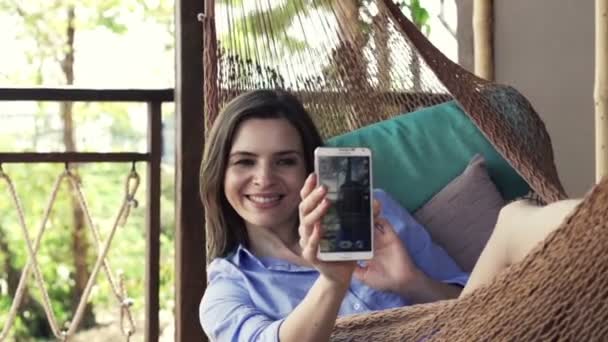 Woman taking selfie photo with cellphone on hammock — Stock Video