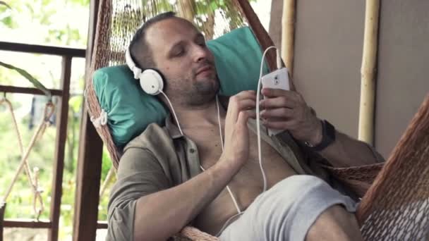 Hombre escuchando música y cantando en hamaca — Vídeo de stock