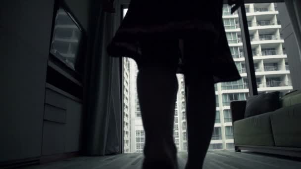 Kvinnan promenader och sträcker armarna vid fönster — Stockvideo