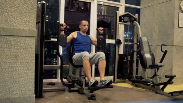 Man exercising on machine in gym at night — Stock Video